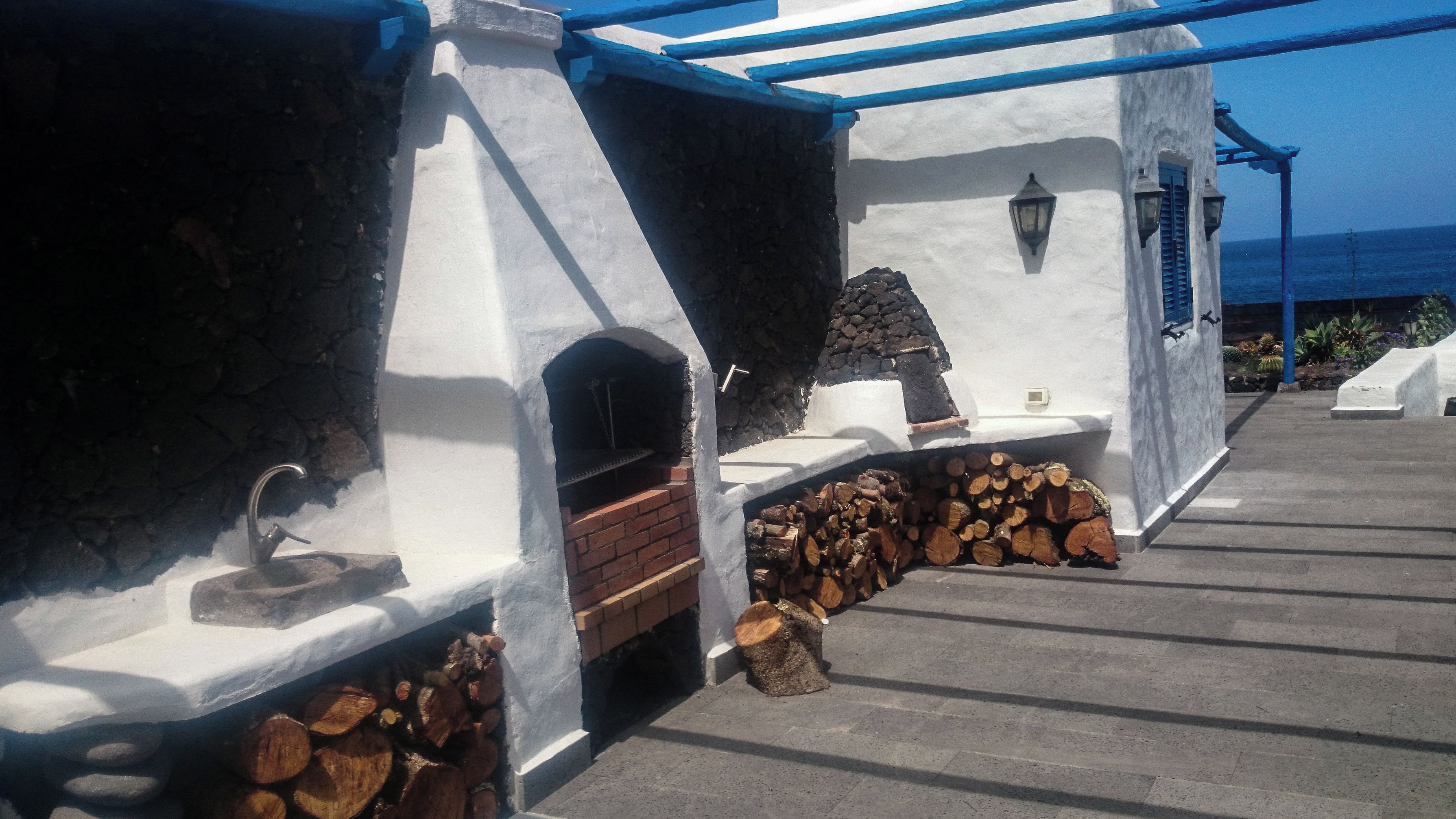 Un edificio de piedra y color blanco con una parrilla integrada y una chimenea de piedra.