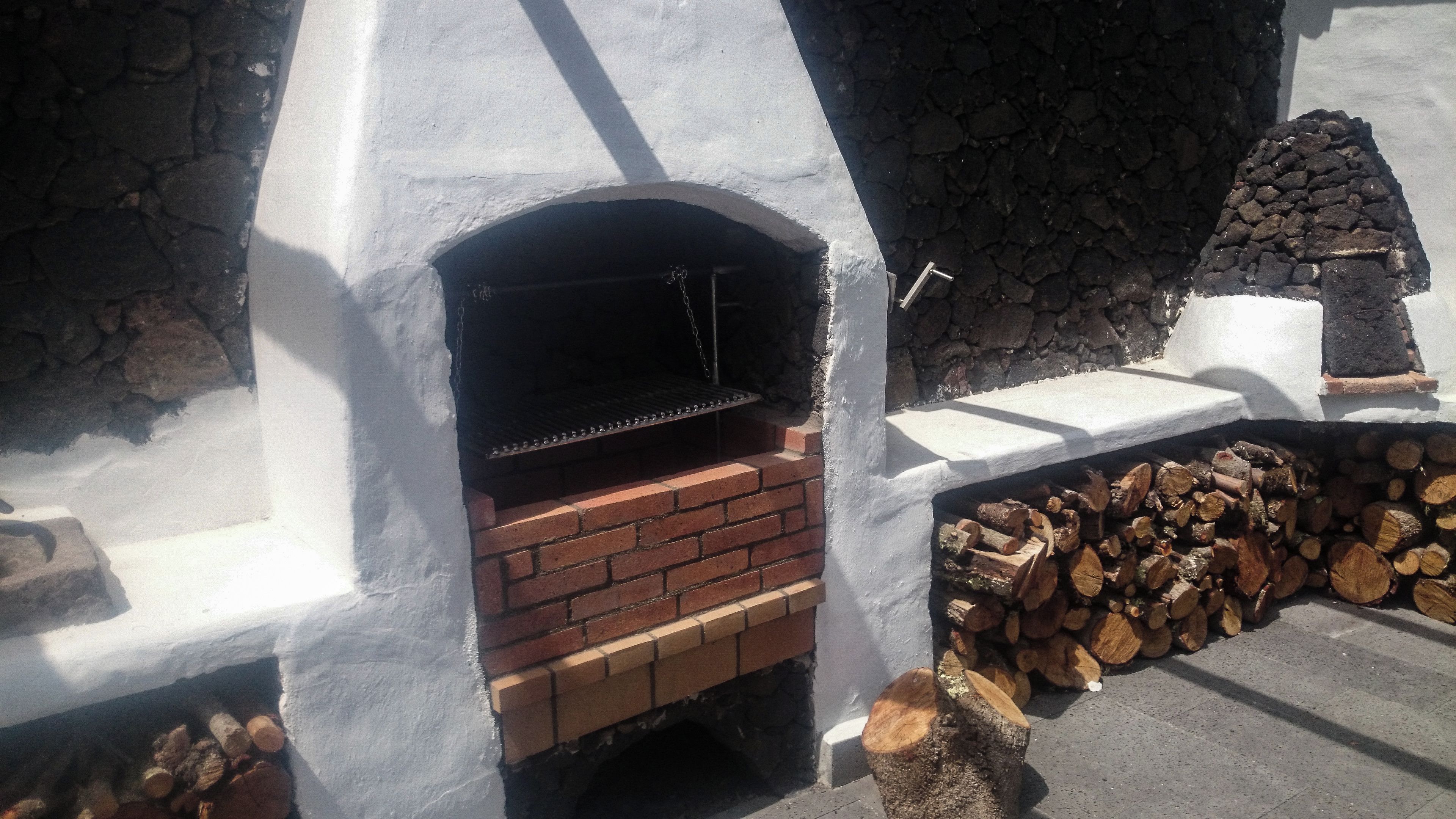 Un horno de ladrillo al aire libre con un fondo de pared de piedra.