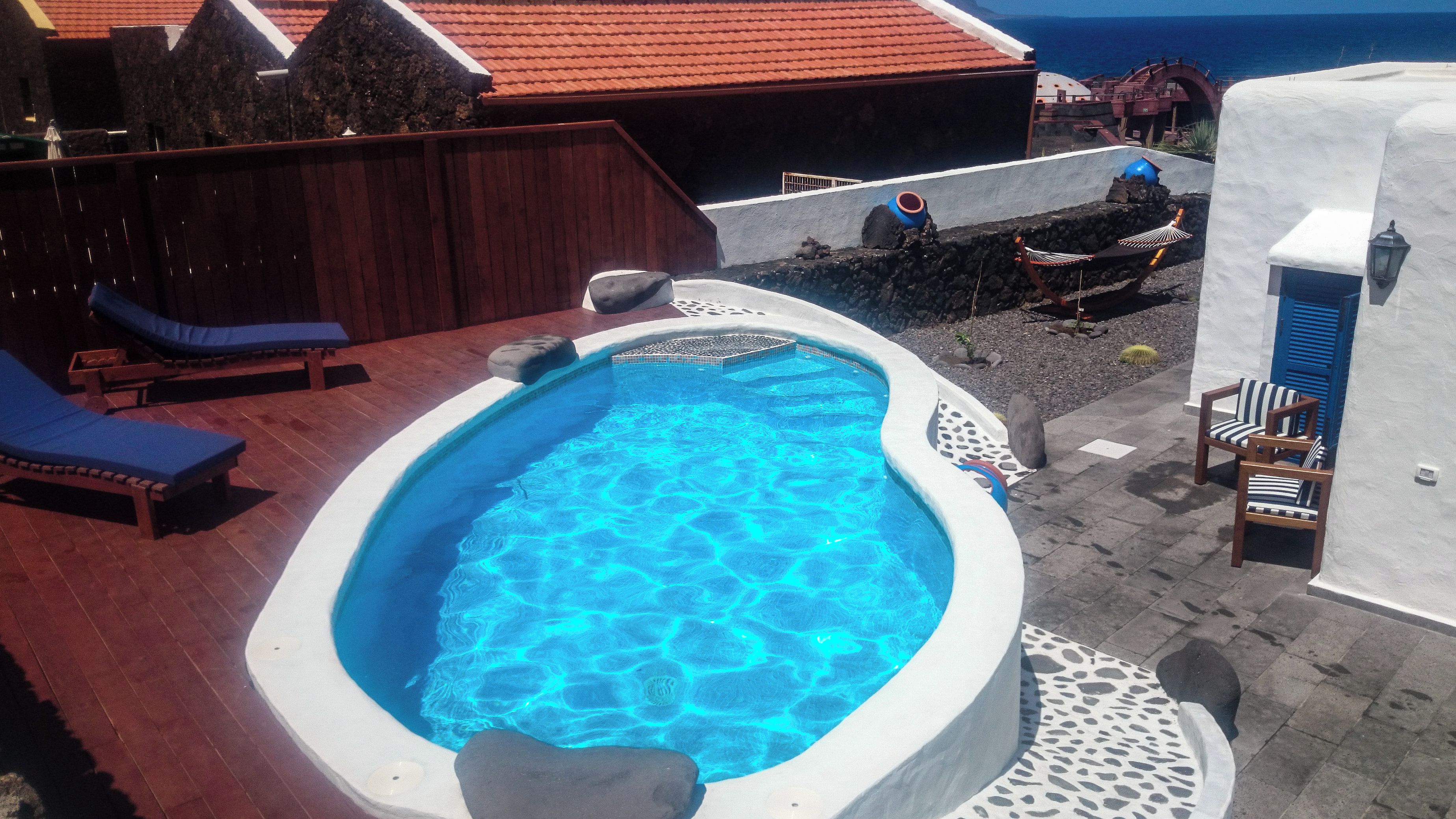 A swimming pool with lounge chairs and a stone wall.