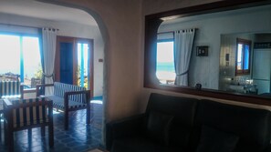 Una habitación con vistas al mar, un comedor con sillas a rayas y una cocina con ventana.