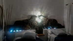 A spa room with a rock formation centerpiece, two beds, and ambient lighting. - Villa Juan (Frontera)