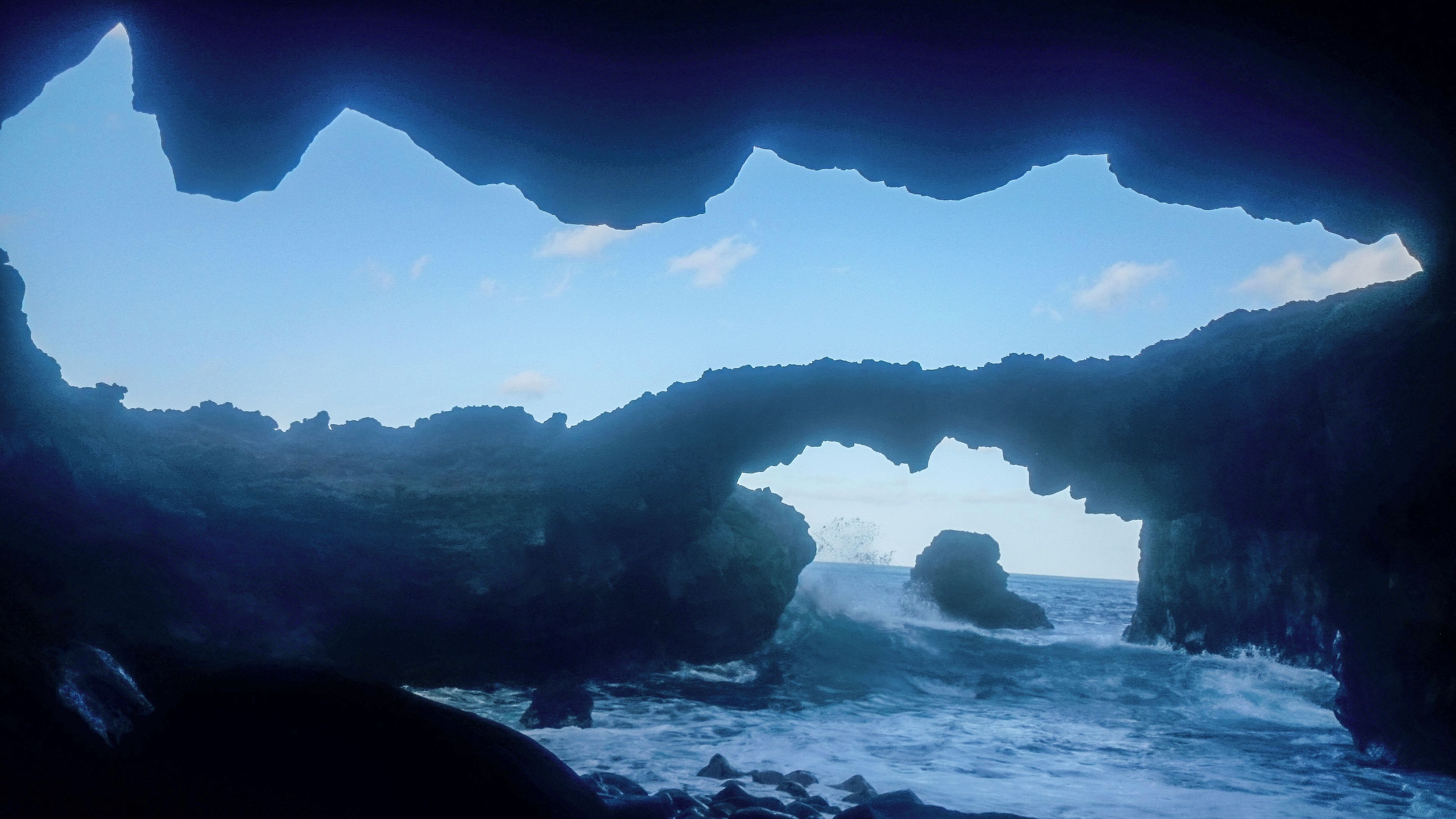 A natural rock formation with an archway leading to the sea.