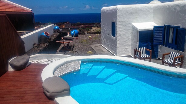 A pool area with a view of the ocean, a hot tub, and two chairs. - Villa Juan (Frontera)