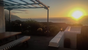 A terrace with a view of the sunset over the sea, featuring a pergola, a bench, and a table. - Villa Juan (Frontera)