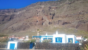 Un edificio costero con muro de piedra, puertas azules y fachada blanca.