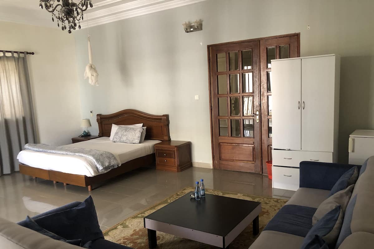 Une chambre à coucher comprenant un lit, une table de chevet, une lampe, une armoire et un canapé.