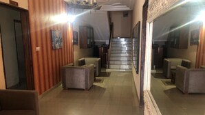 A hotel lobby with a staircase, seating areas, and a large mirror reflecting the space. - Hotel Le Littoral des Almadies (Dakar)
