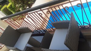 A balcony with wicker furniture and a view of a blue swimming pool. - Hotel Le Littoral des Almadies (Dakar)