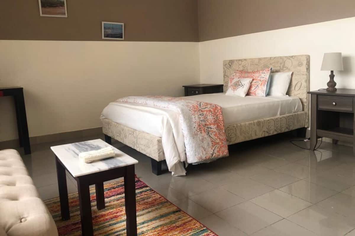 Une chambre à coucher avec un lit, des tables de chevet, une chaise et un tapis.