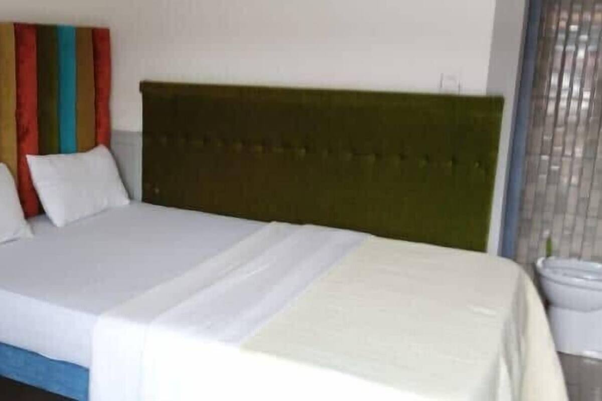 A bed with a green headboard, white bedding, and colorful striped curtains.
