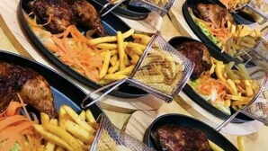 A table set with multiple plates of food, including meat and fries. - Sweet Stay Guest House (Kigali)