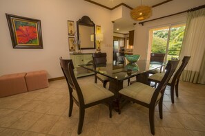 A dining area with a glass table and chairs, a bench, and a view of the outdoors. - Los Suenos Resort Veranda 8F (Jacó)