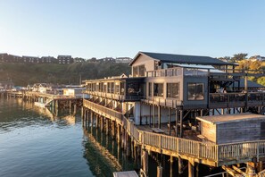 A waterfront property with multiple decks, outdoor seating, and a dock extending into the water. - Anchor Lodge  (Fort Bragg)