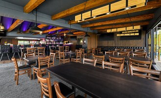 Un restaurante con una larga mesa común, varios reservados y una zona de bar.