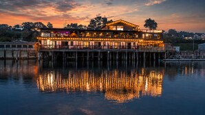 A waterfront hotel with multiple levels, outdoor seating, and a dock. - Anchor Lodge  (Fort Bragg)
