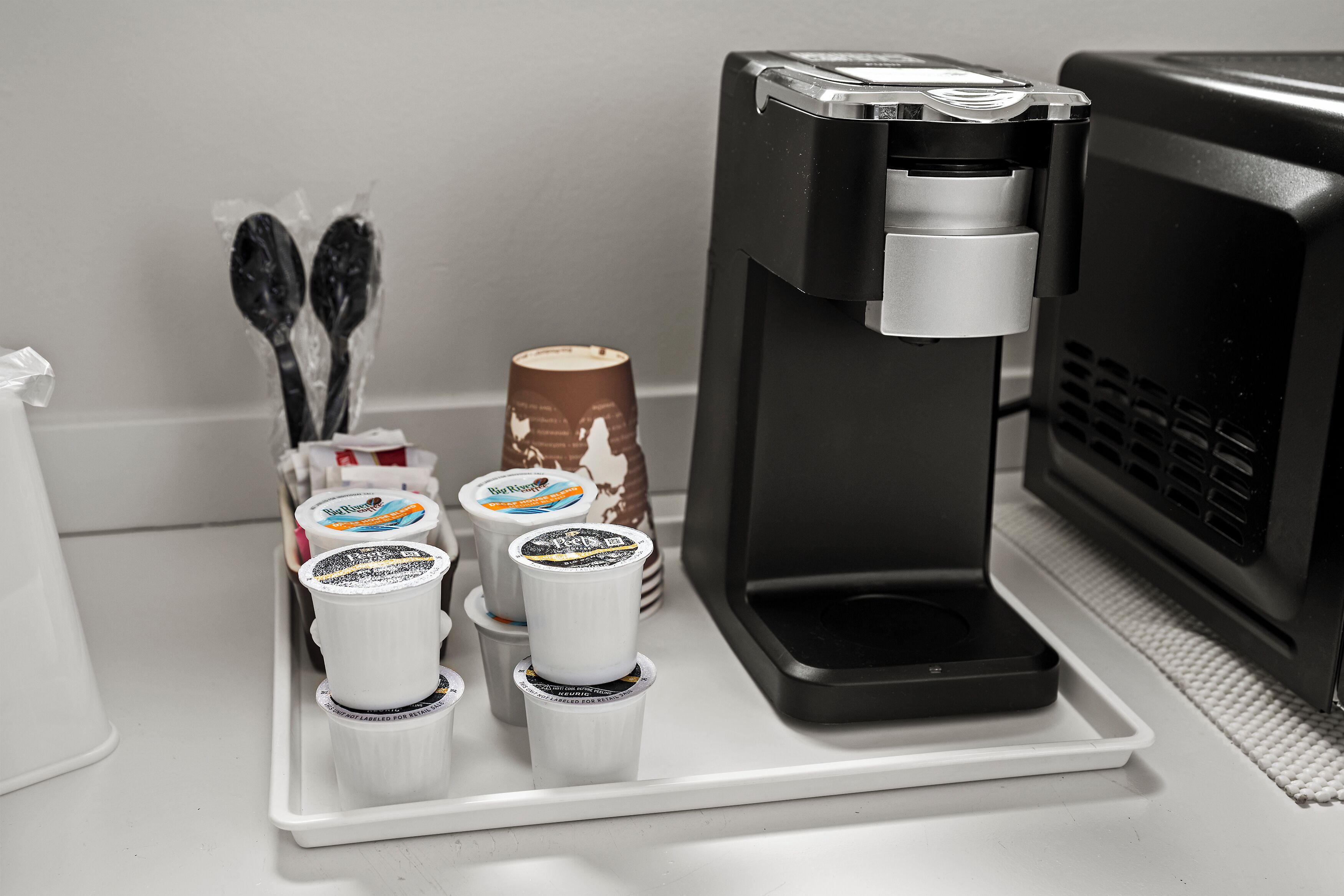 Una macchina da caffè con bicchieri e cucchiaini usa e getta su un vassoio.
