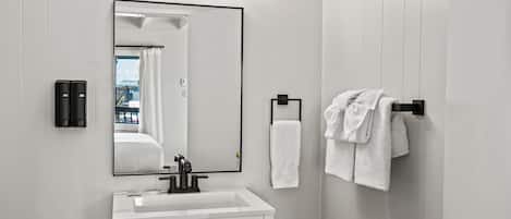 Un baño con un lavamanos blanco, un espejo y dos luces empotradas.