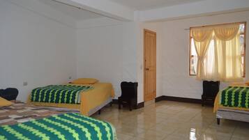 Habitación de hotel con dos camas, una puerta de madera y una ventana con cortinas.