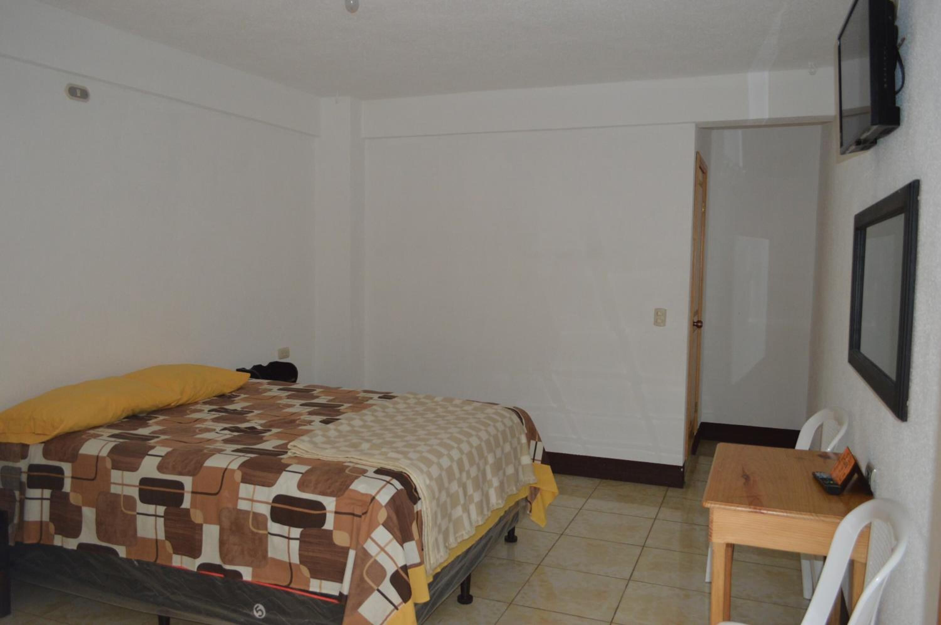 A bedroom with a bed, a desk, and a chair.