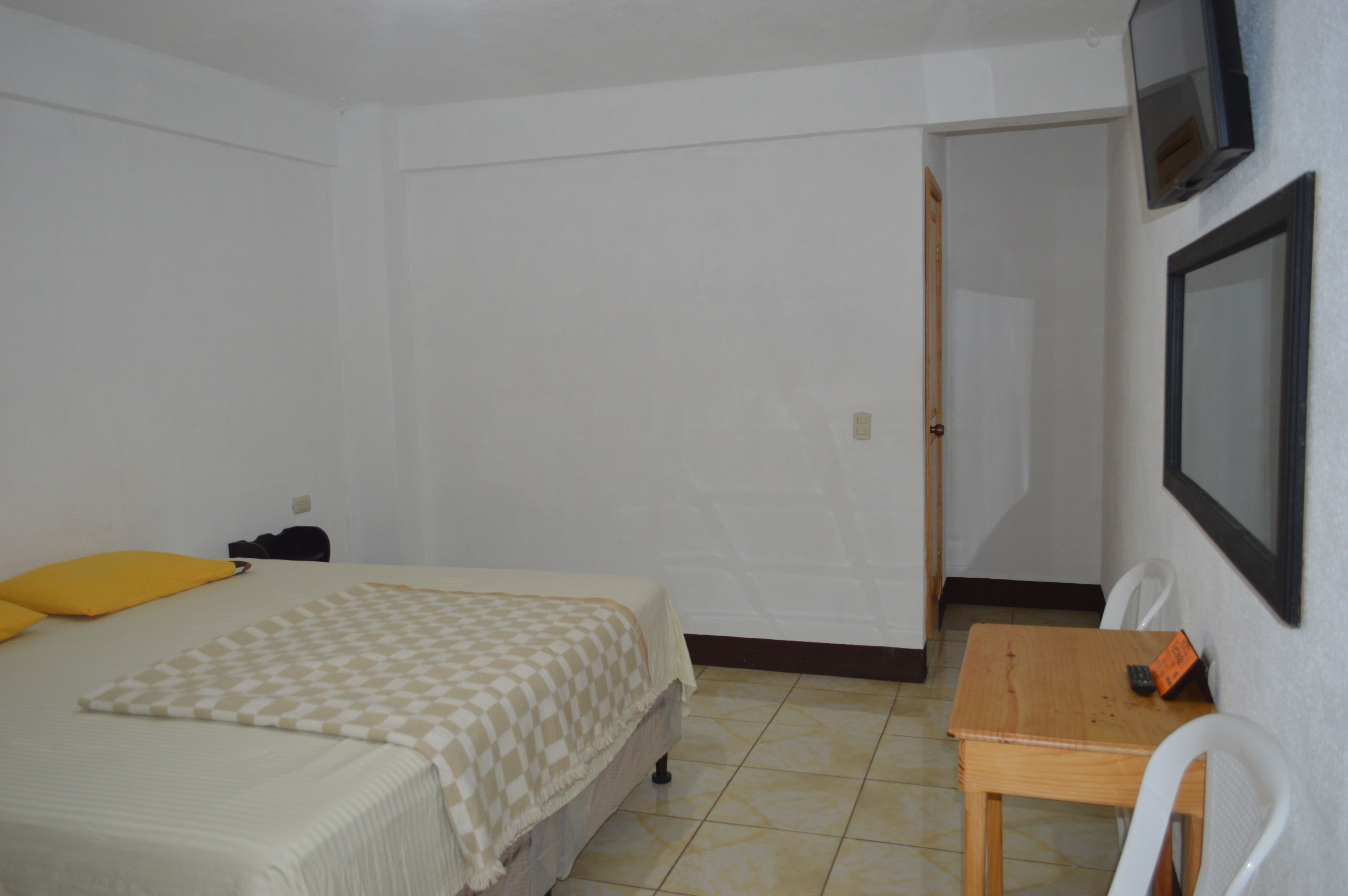Een kleine, schone kamer met een bed, een bureau en een stoel.