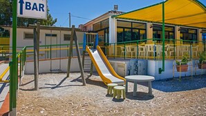 A playground with a slide, a table, and a sign indicating a bar direction. - Playa Colorada (Gaeta)
