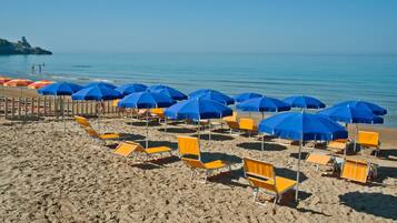 Een privéstrand, ligstoelen aan het strand, parasols