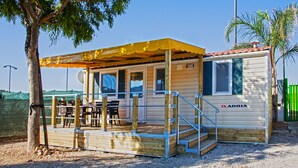 A small wooden structure with a yellow awning, a staircase, and a table with chairs outside. - Playa Colorada (Gaeta)