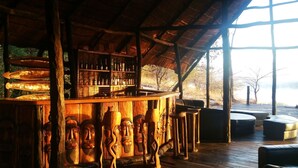 A rustic bar area with wooden furniture and a thatched roof.