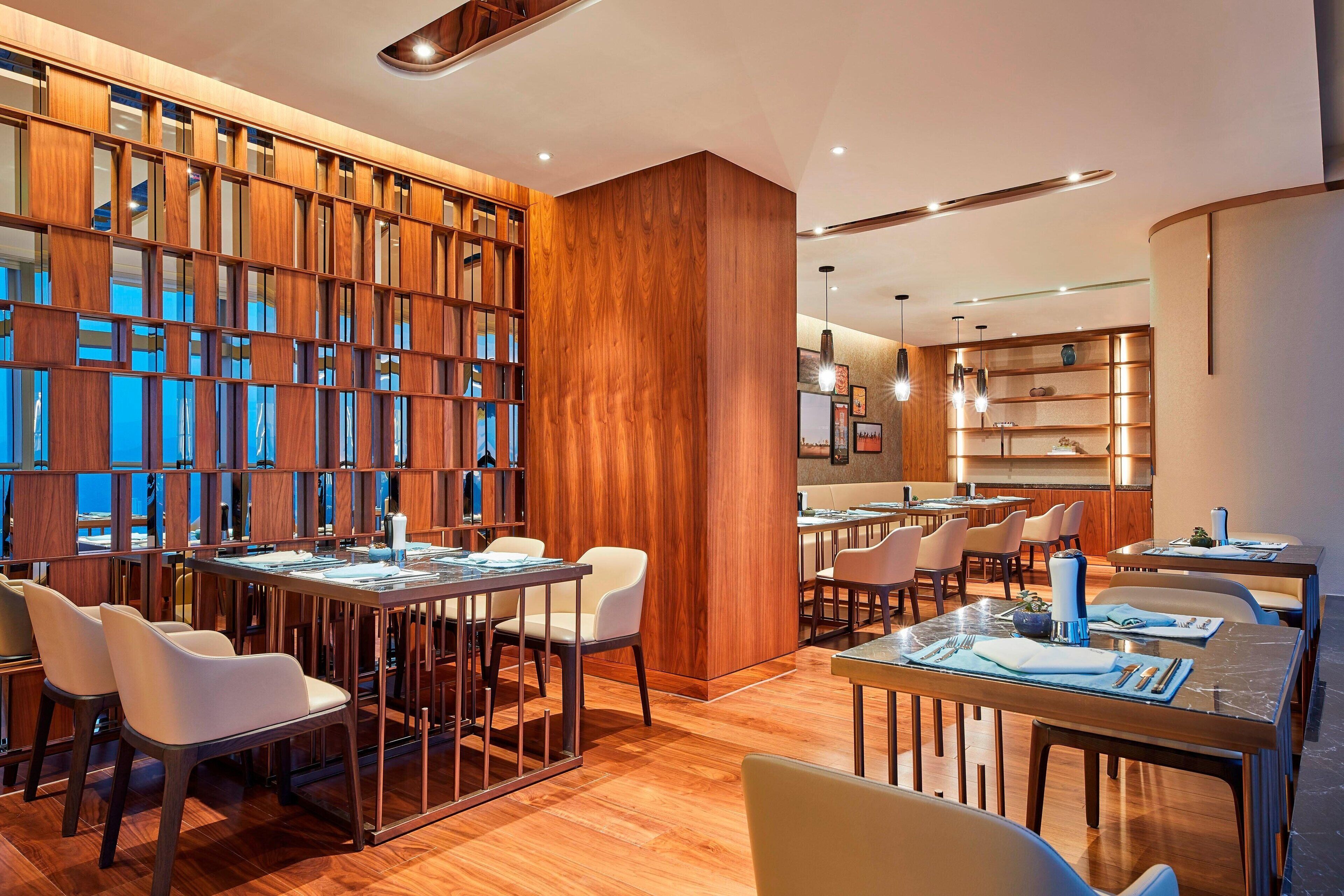 Un comedor moderno con paneles de madera, mesas y sillas.
