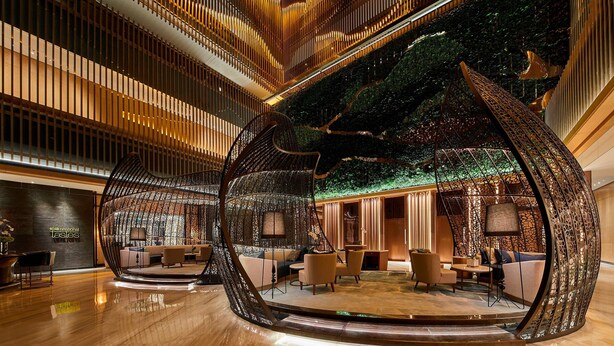 Un interior moderno con una zona de estar de diseño curvo, suelo de madera y una pared verde con motivo de árbol.