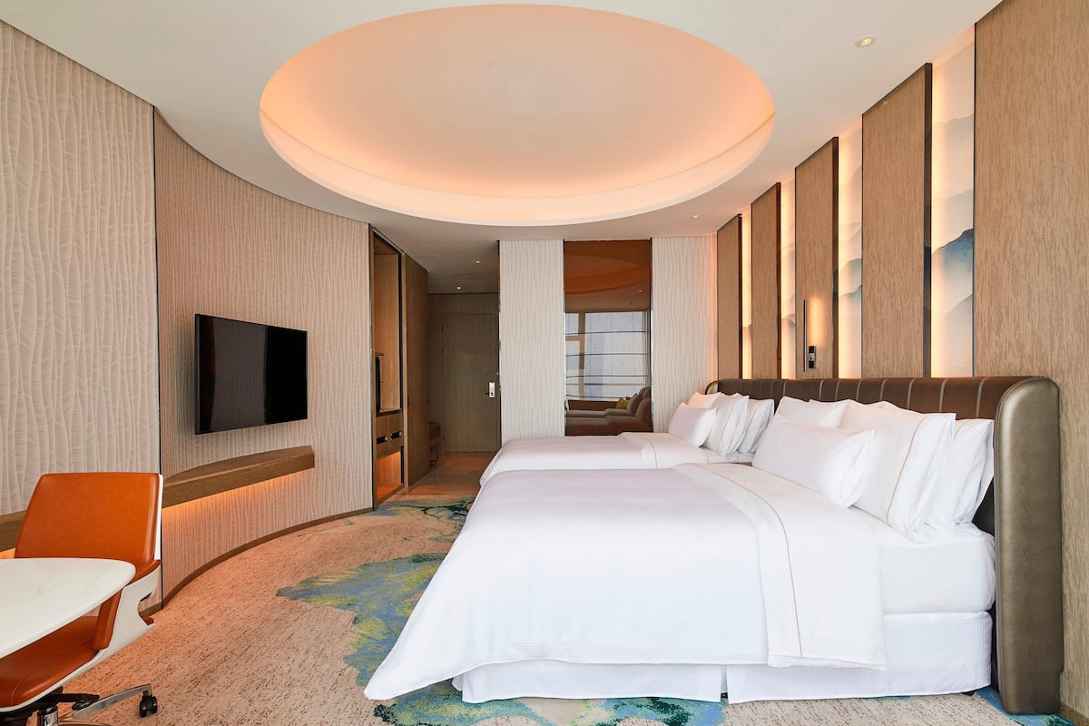 Ein Hotelzimmer mit einem großen Bett, einem Schreibtisch und einem Flachbildfernseher.
