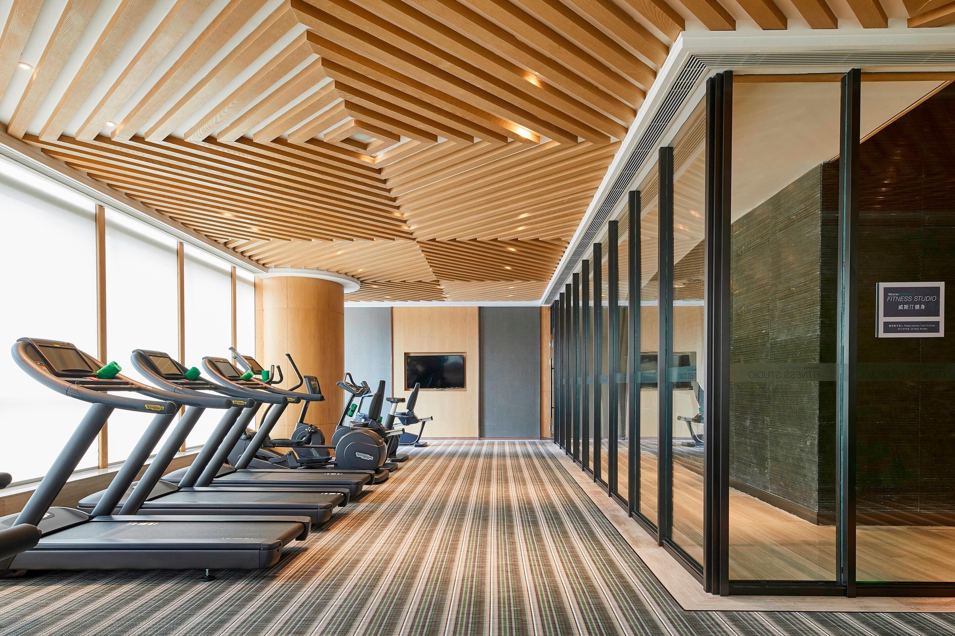 A gym with treadmills, stationary bikes, and a wall-mounted TV.