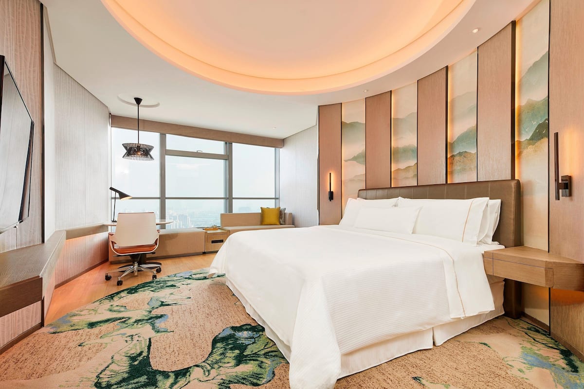 Ein modernes Hotelzimmer mit einem großen Bett, einem Schreibtisch und Blick auf die Stadt.