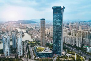A high-rise building with the name "WESTIN" prominently displayed, surrounded by a dense urban area with other high-rise buildings and a river in the background. - The Westin Wenzhou (Wenzhou)