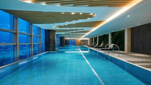 Una piscina interior moderna con vistas al paisaje urbano a través de amplios ventanales.