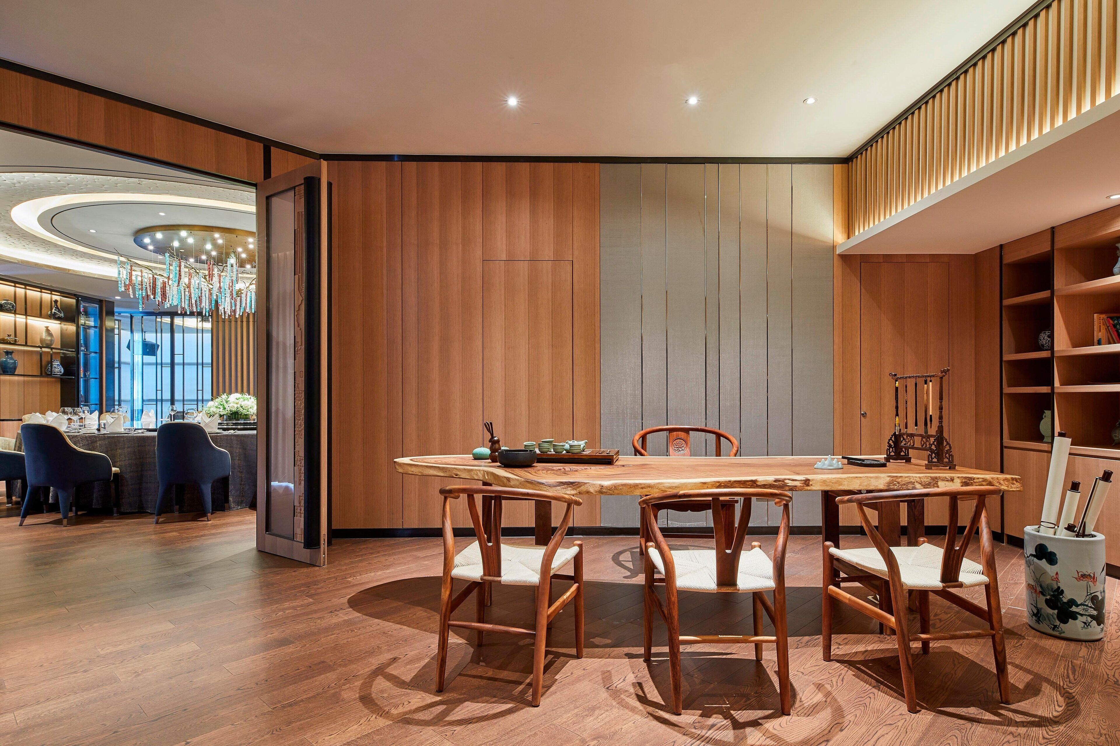 Un espace repas moderne avec une table et des chaises en bois, une cuisine en arrière-plan et un vase décoratif sur le côté.