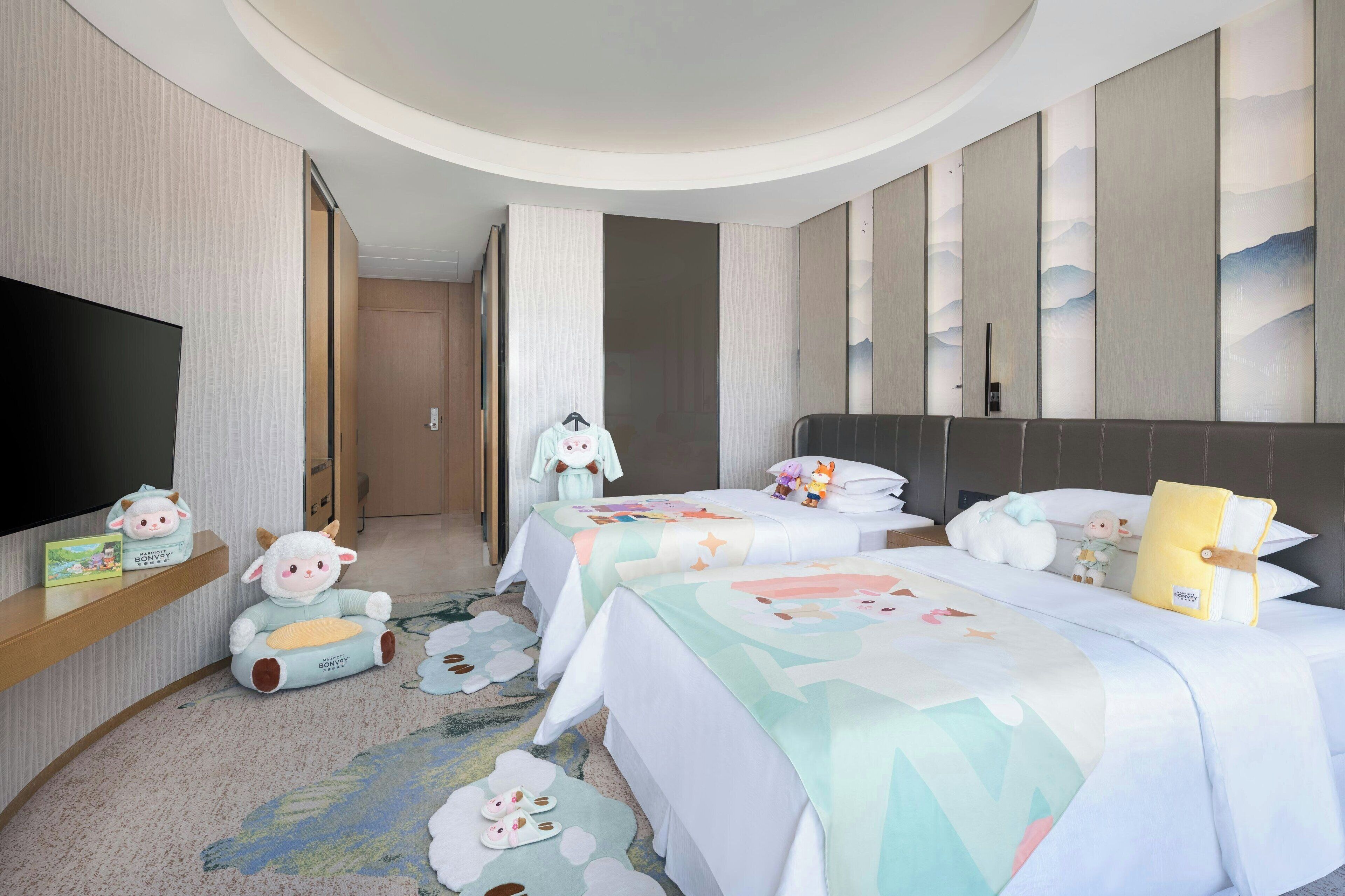 A hotel room with two beds, a TV, and a children's play area.