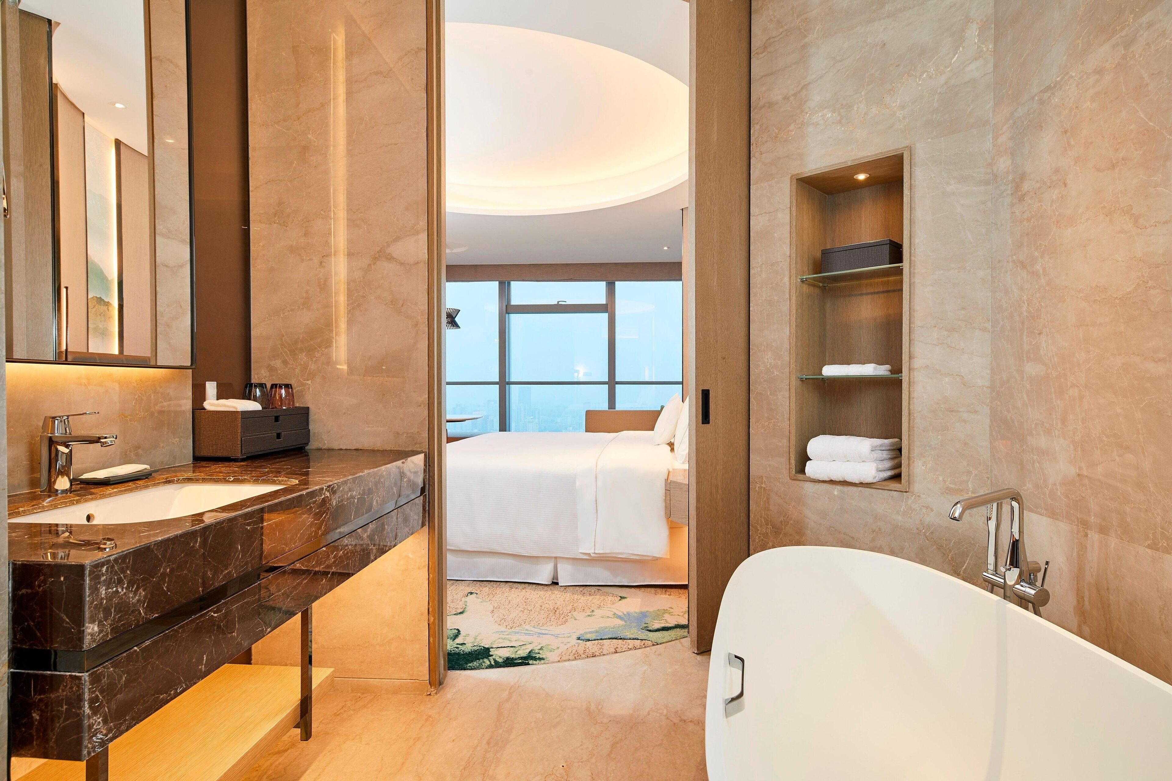 Un baño moderno con tocador de mármol, una bañera independiente y un espejo grande.