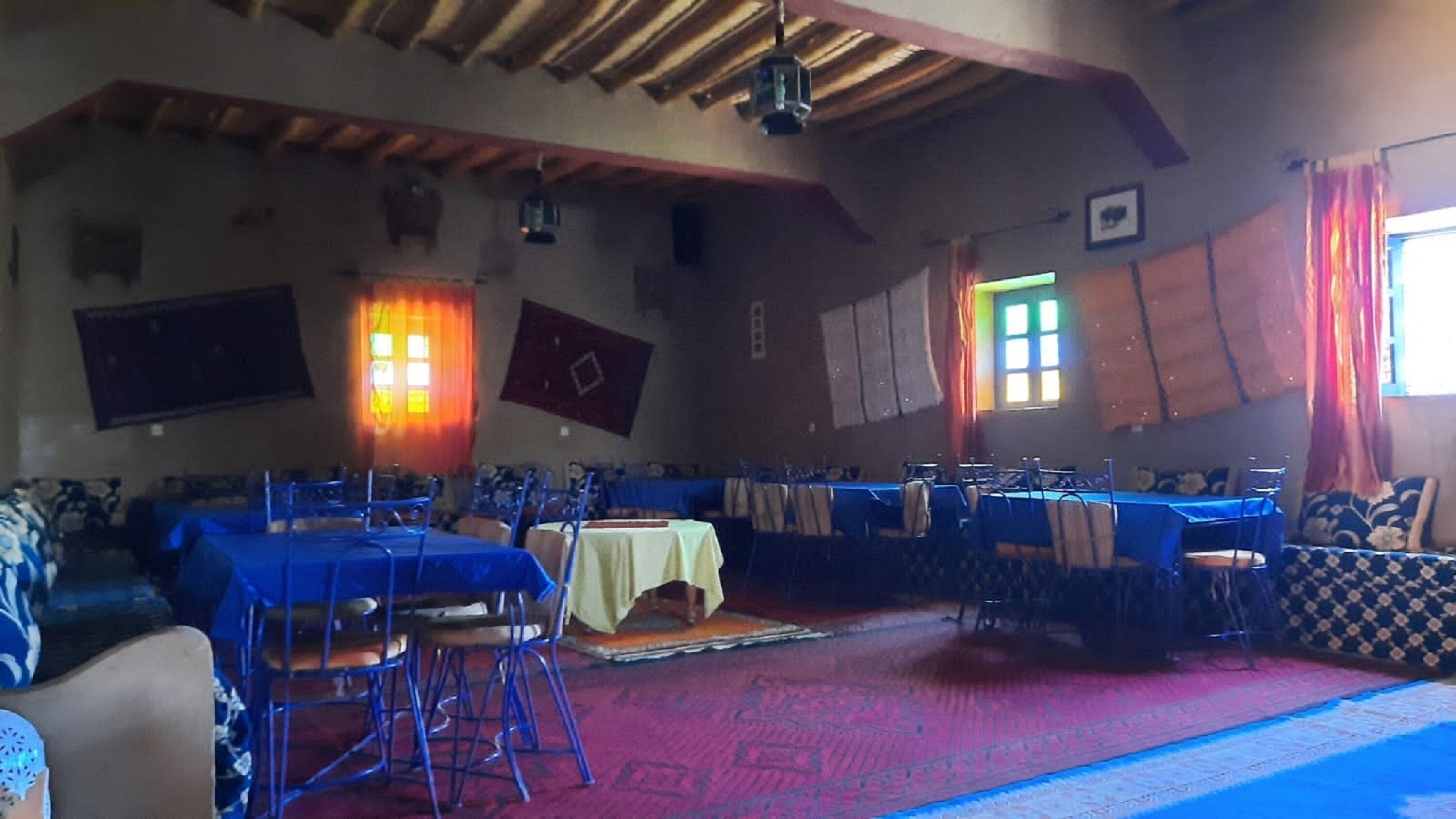 A spacious hall with high ceilings and a wooden beam structure. Tables and chairs are arranged for dining.