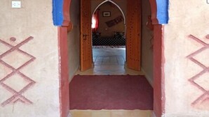 An arched doorway with a red and blue arch, leading to a room with a patterned floor. - Riad Tadarte Merzouga Desert Tours (Taouz)