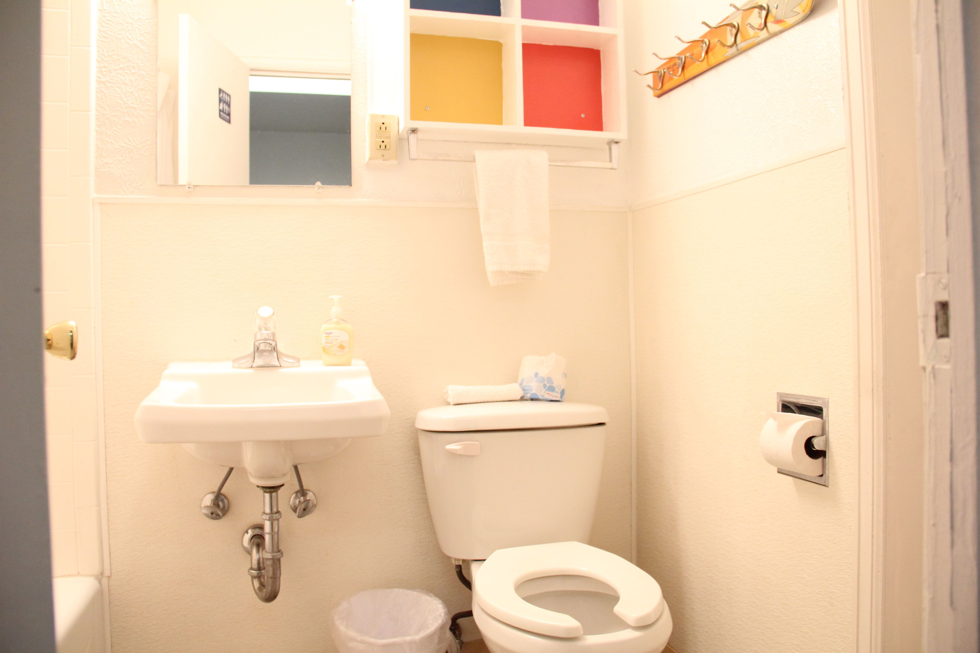 Une petite salle de bain avec un lavabo blanc, des toilettes et une poubelle.