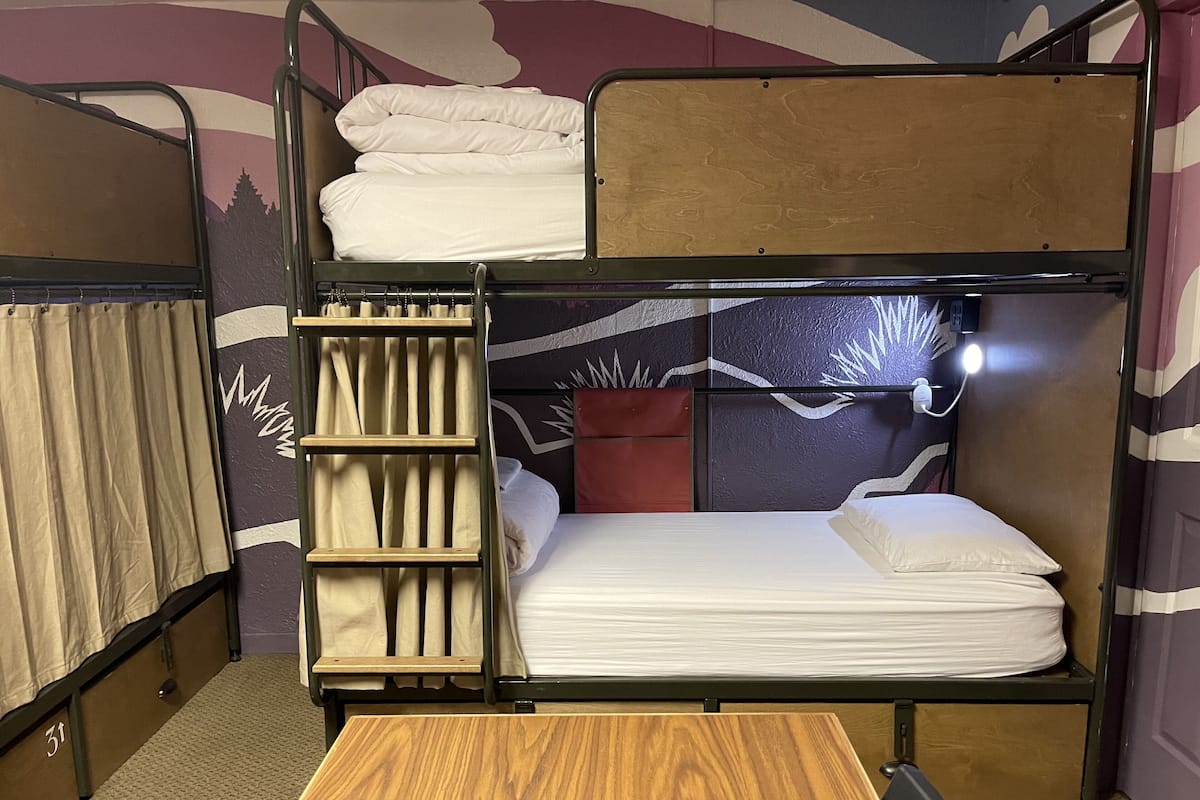 Una cama litera con una mesa de madera en una habitación con un papel tapiz estampado.