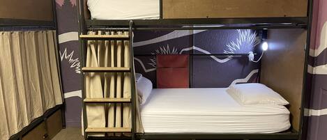 A bunk bed with a wooden table in a room with a patterned wall.