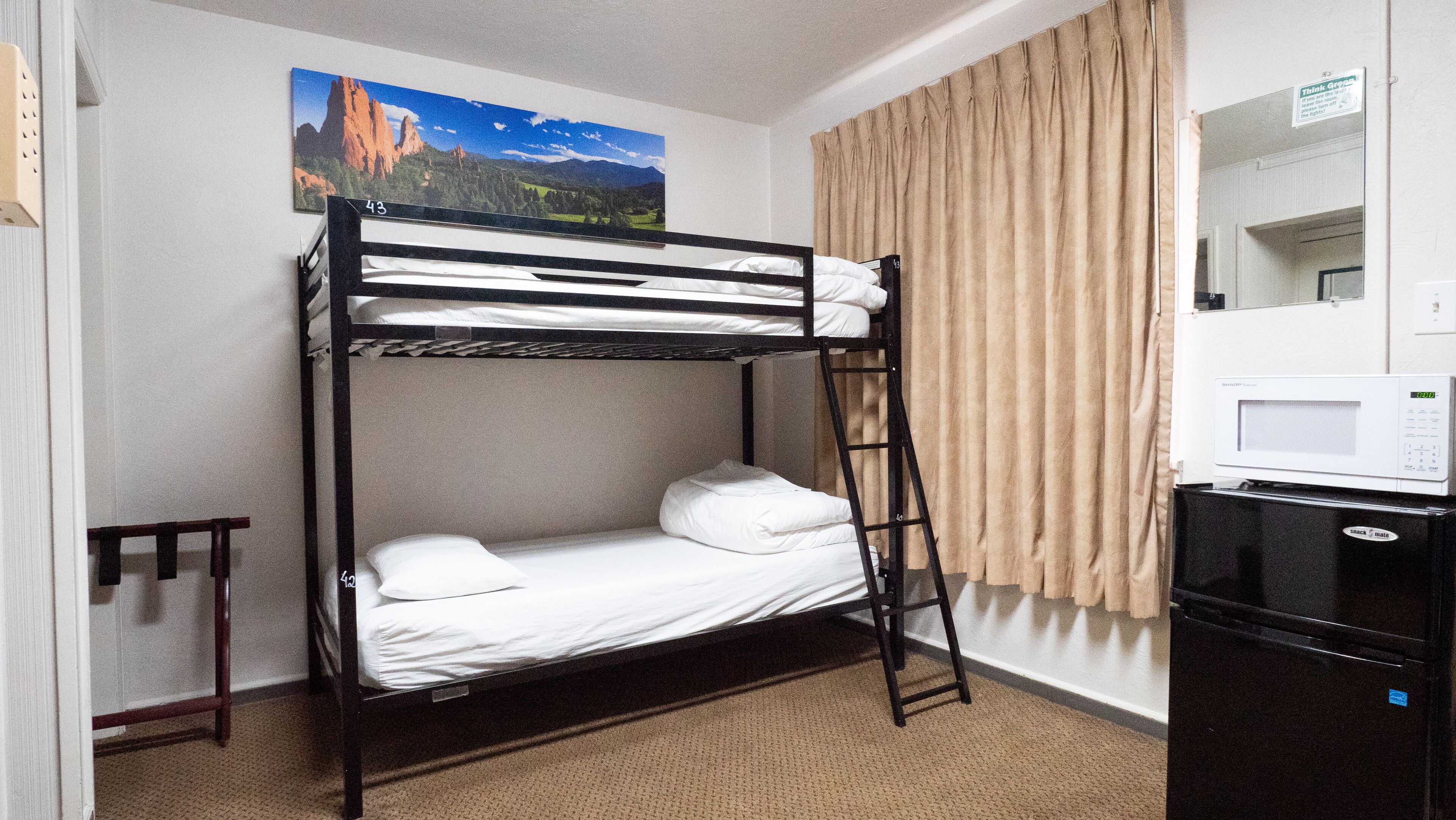 A bunk bed room with a microwave and a refrigerator.