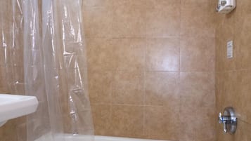 A bathroom with a bathtub, shower, and a towel rack.