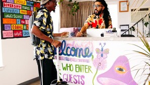 A reception desk with a colorful welcome sign, a plant, and a wall with motivational posters. - RAD Hostel (Colorado Springs)