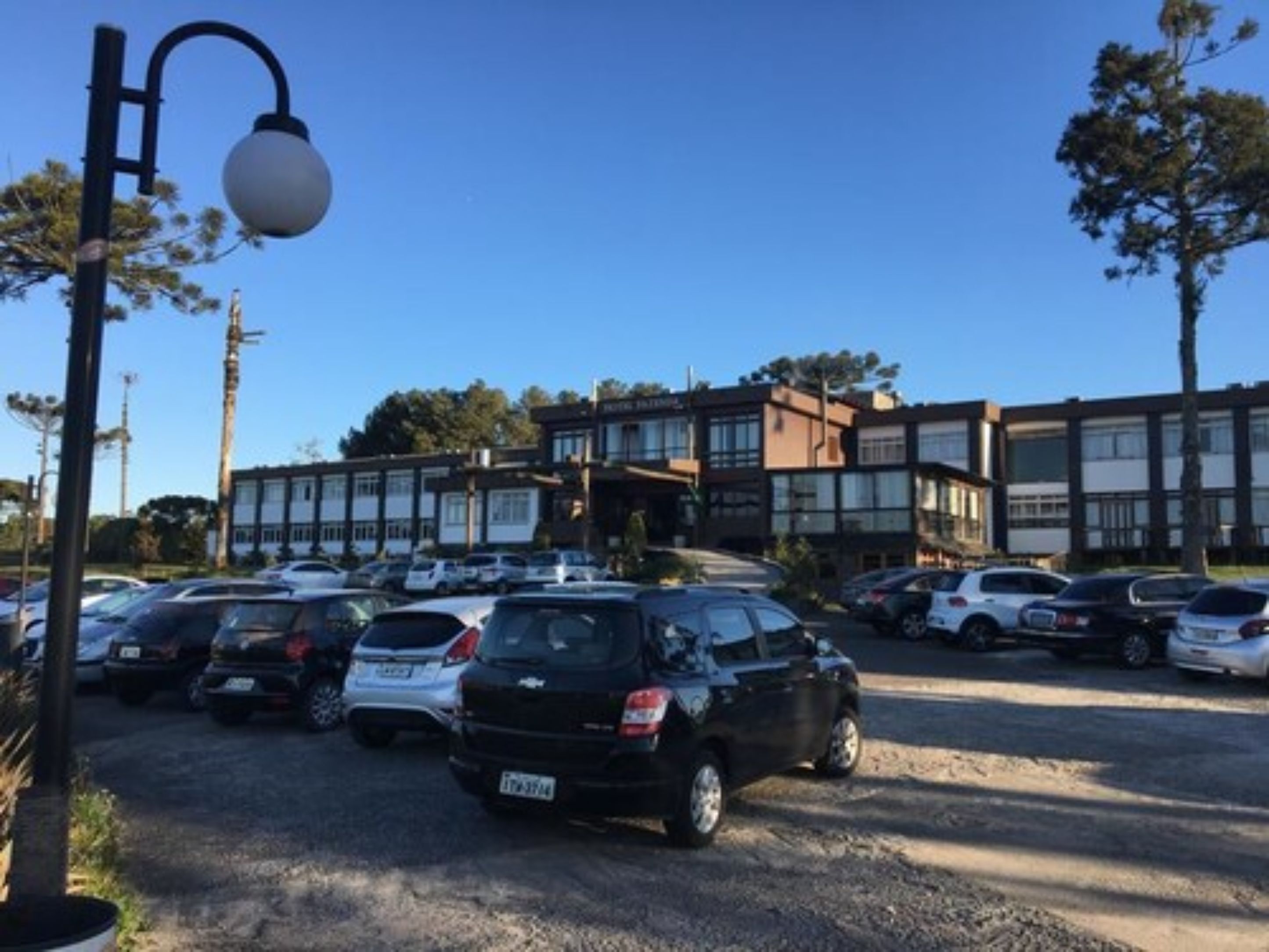 A parking lot with multiple cars, a street lamp, and a building with large windows and a modern design.