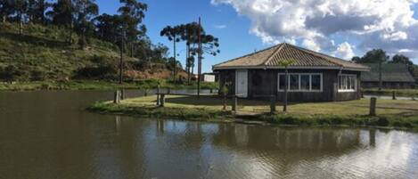 Un edificio junto al lago, de diseño sencillo y rústico, rodeado de árboles y una masa de agua tranquila.