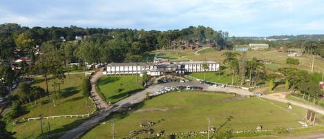 A large building with multiple wings, surrounded by green fields and a road.