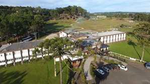 A large building with multiple windows and a parking lot with several cars. - Hotel Fazenda Pampas (Canela)